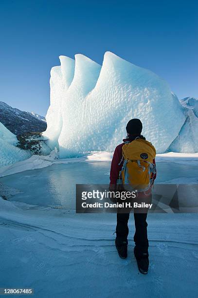 woman hiking with a backpack in front of an ice formation on the knik glacier, winter, chugach mountains, alaska, usa, march 2011 - alaska location stockfoto's en -beelden