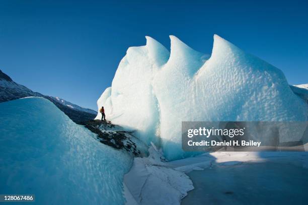 woman hiking on the ice in front of an ice formation on the knik glacier, winter, chugach mountains, alaska, usa, march 2011 - knik glacier stock pictures, royalty-free photos & images