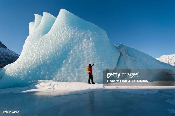 woman hiking in front of an ice formation on the knik glacier, winter, chugach mountains, alaska, usa, march 2011 - gletsjer stockfoto's en -beelden