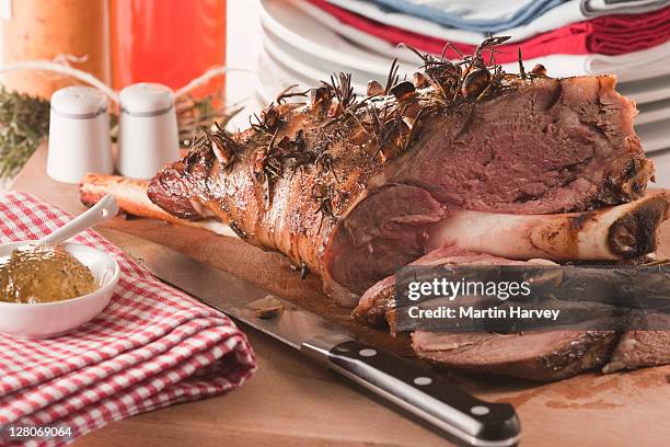 cooked seasoned leg of lamb on wooden board - lammkeule stock-fotos und bilder