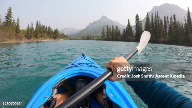 pov past kayakers arms paddling down a mountain river - rocky mountains north america stock-fotos und bilder