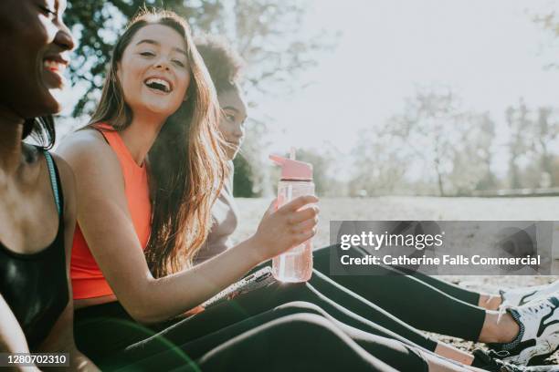 three girls in sportswear relax outside in the sun - törstig bildbanksfoton och bilder