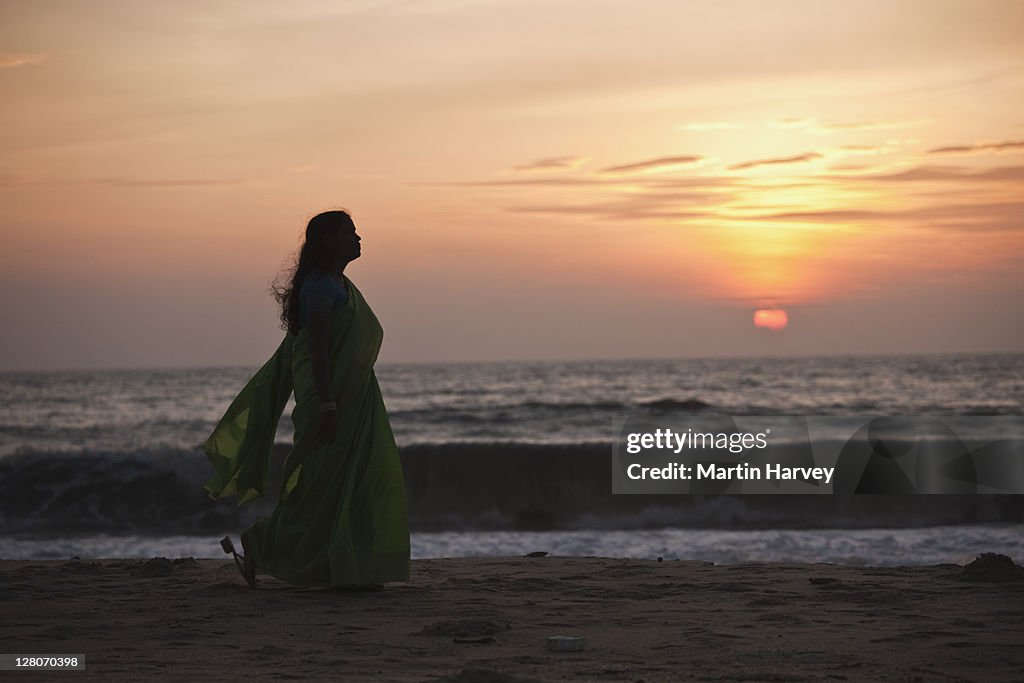 Woman (28 years old) in traditional green sari walking on Marari beach Alappuzha, Kerala, India