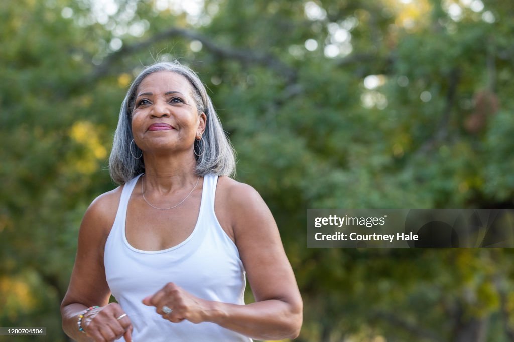 Mujer mayor corriendo en el parque público