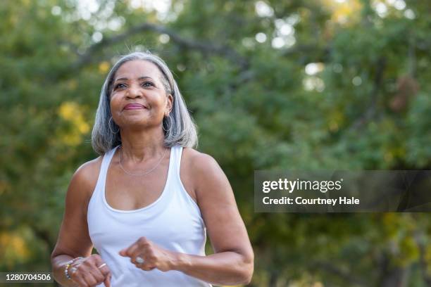 hogere vrouw die in openbaar park aan het joggen is - active seniors outdoors stockfoto's en -beelden
