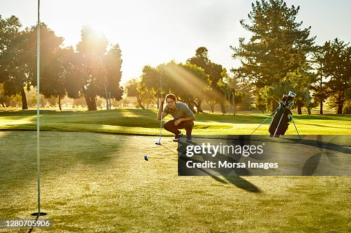 Golfer Crouching While Analyzing On Golf Field Golfer Crouching While Analyzing On Golf Field