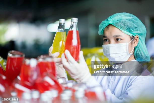 female workers checking glass bottle of the basil seed mixed pineapple and lychee fruit drink product. food and beverage industry - food safety stock-fotos und bilder