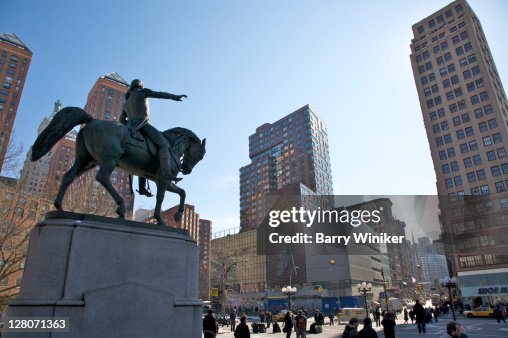 Equestrian statue of George Washington, Across the street is One Union Square South with kinetic wall sculpture and digital clock expelling bursts of steam, titled Metronome, New York City, NY, USA