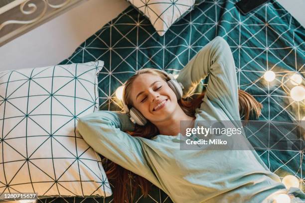 portrait of woman relaxing in bed and listening music - podcast headphones stock pictures, royalty-free photos & images