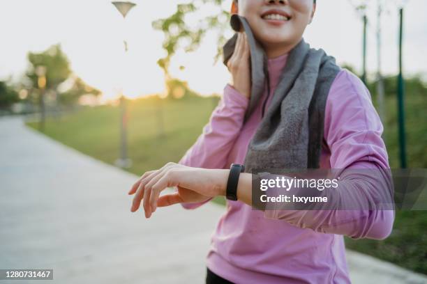 jeune femme asiatique sportive vérifiant le traqueur de forme physique sur son poignet - podomètre photos et images de collection