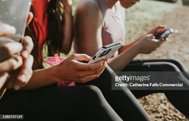 three woman holding their mobile phones outside and looking at the screens - social media stock pictures, royalty-free photos & images