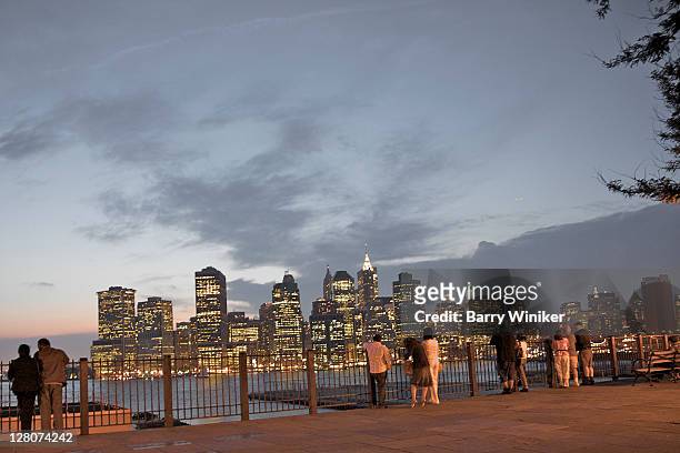 people at brooklyn heights esplanade looking at office towers of lower manhattan at dusk, with east river - brooklyn heights stock pictures, royalty-free photos & images