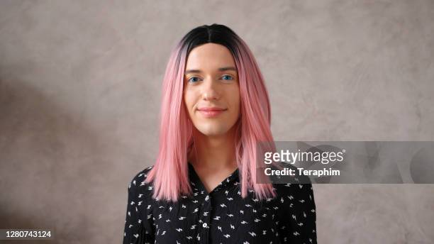transwoman in black dot dress with pink wig poses on beige - beige dress stock pictures, royalty-free photos & images