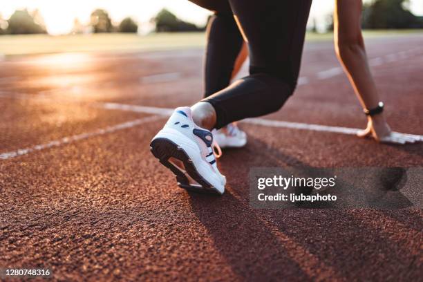 primer plano de atleta mujer preparándose para empezar a correr en la pista. concéntrese en las zapatillas - sports track fotografías e imágenes de stock