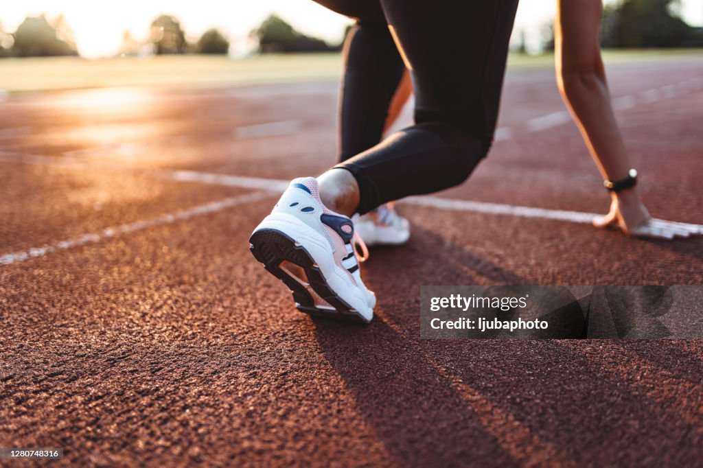 女運動員準備開始在賽道上跑步的特寫。專注於運動鞋。
