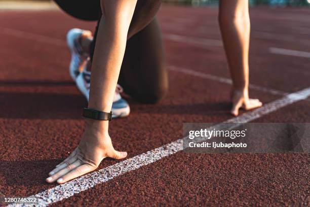 atleta femenina en la línea de salida de una pista del estadio - posicionamiento fotografías e imágenes de stock
