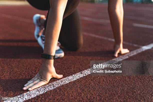 vrouwelijke atleet op de lopende lijn van een stadionspoor - starting block stockfoto's en -beelden