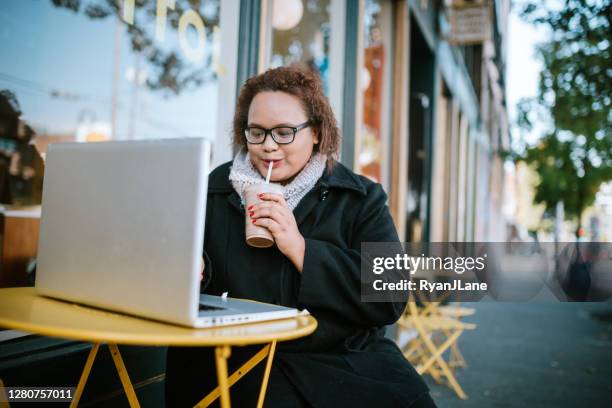 woman working on laptop outside coffee shop - fall in seattle stock pictures, royalty-free photos & images