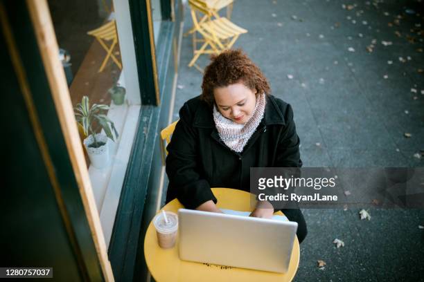 mujer trabajando en el ordenador portátil fuera de la cafetería - fall in seattle fotografías e imágenes de stock