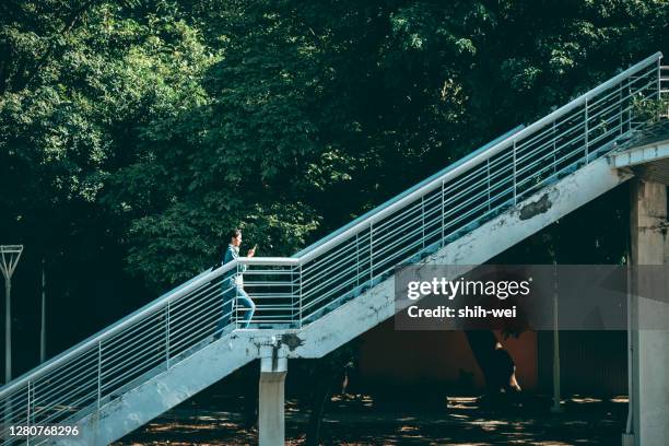 donna che usa lo smartphone camminando per strada - ponte pedonale foto e immagini stock