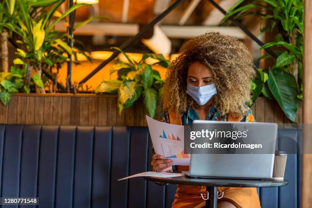 businesswoman wears her mask and does her job while waiting for her food in the restaurant - colombia business breakfast meeting stock pictures, royalty-free photos & images