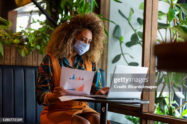 businesswoman wears her mask and does her job while waiting for her food in the restaurant - colombia business breakfast meeting stock pictures, royalty-free photos & images