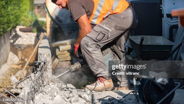 man using a jackhammer to break up concrete block in the backyard - jackhammer stock pictures, royalty-free photos & images