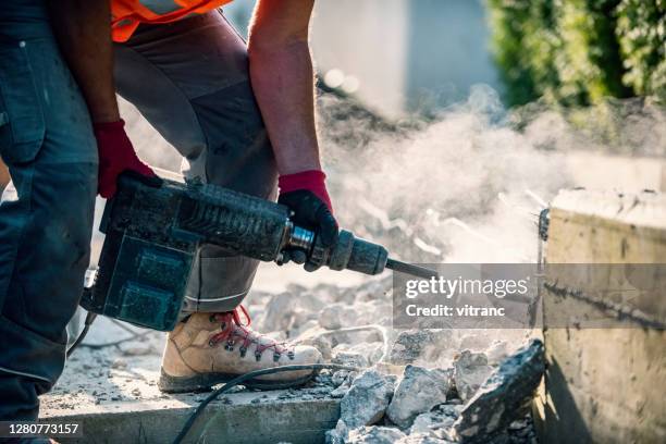 man using a jackhammer to break up concrete block in the backyard - jackhammer stock pictures, royalty-free photos & images