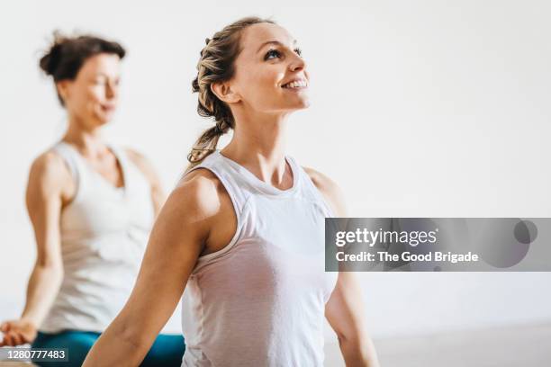 happy woman looking up while practicing yoga in studio - unterhemd stock-fotos und bilder