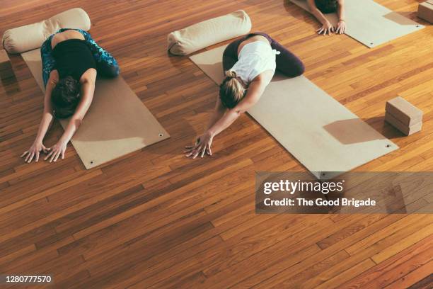 high angle view of female friends practicing yoga in child's pose on exercise mats in studio - child yoga elevated view stock pictures, royalty-free photos & images