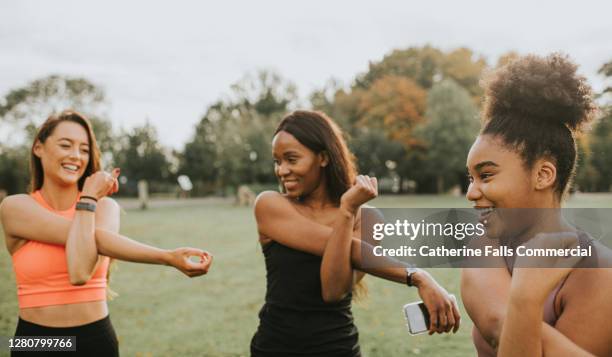 woman stretching their arms during an outdoor exercise session - group of people flexing biceps stock pictures, royalty-free photos & images