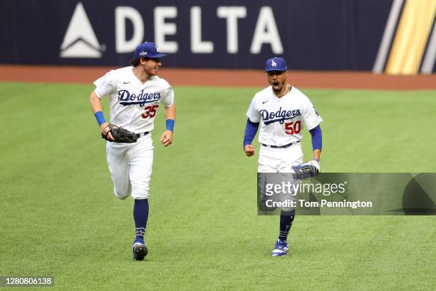 Mookie Betts of the Los Angeles Dodgers celebrates with Cody Bellinger after catching a fly ball at the wall on a hit by Marcell Ozuna of the Atlanta...
