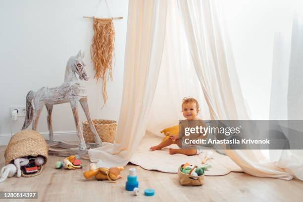 children's playroom full of toys. beautiful decoration nursery with natural macrame decoration, organic canopy, wicker baskets and wood toys. zero waste and ecological concept. - ludoteca foto e immagini stock