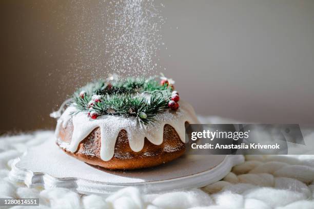 traditional christmas lemon bundt cake decorated with spruce branch and cranberrys. - christmas cake stock-fotos und bilder