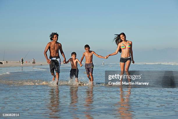 indian family (25, 7, 11, 20 years old) dressed in swim wear, playing in shallow waves, muizenberg beach, cape town, western cape province, south africa - 6 7 years stock-fotos und bilder