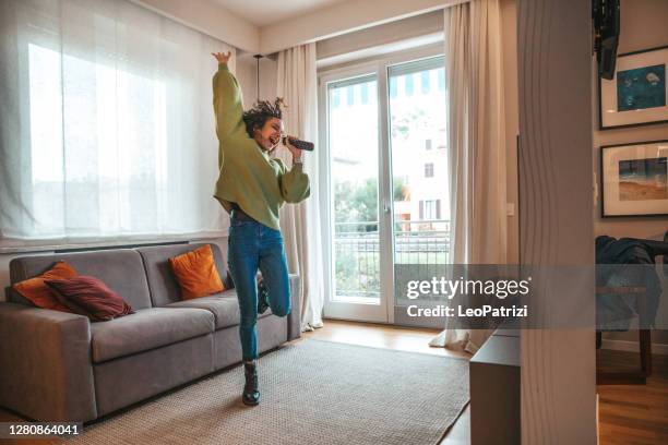 mujer feliz cantando en la sala de estar - chica bailando fotografías e imágenes de stock