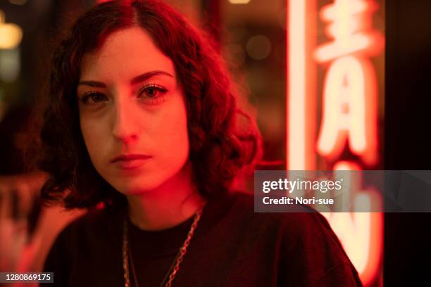 a woman posing in front of the red neon light - red light portrait stock pictures, royalty-free photos & images