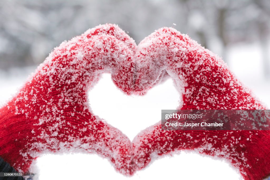 Woman making heart symbol with snowy hands