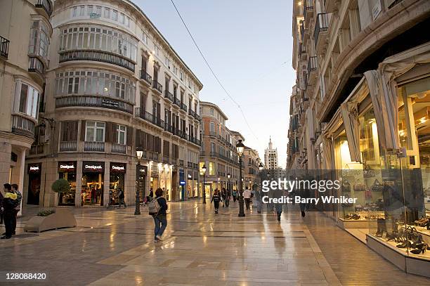 upscale shops and shoppers at dusk on pedestrian street calle de larios, malaga, costa del sol, andalucia, spain - malaga province stock pictures, royalty-free photos & images