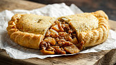 Traditional Cornish pasty filled with beef meat, potato and vegetables on black plate