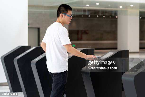man passing through ticket gate with mobile phone - entering turnstile stock pictures, royalty-free photos & images