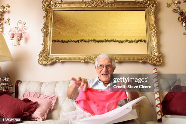 senior man holding up pink panties - christmas surprise stock pictures, royalty-free photos & images