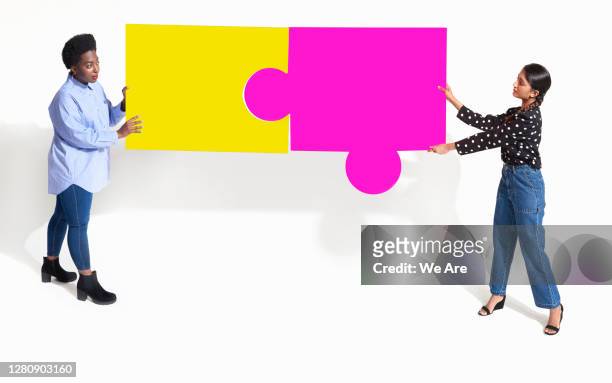 women with jigsaw pieces - creative collaboration holding stockfoto's en -beelden