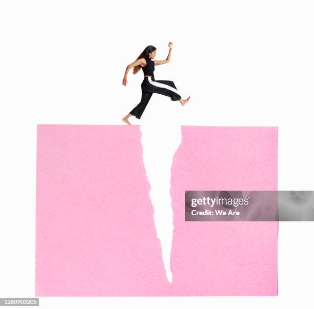 woman leaping over crack - schreiten stock-fotos und bilder