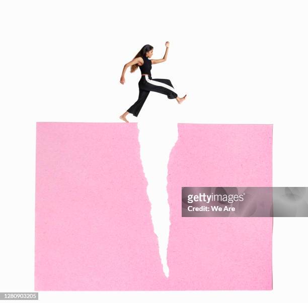 woman leaping over crack - business courage stock pictures, royalty-free photos & images