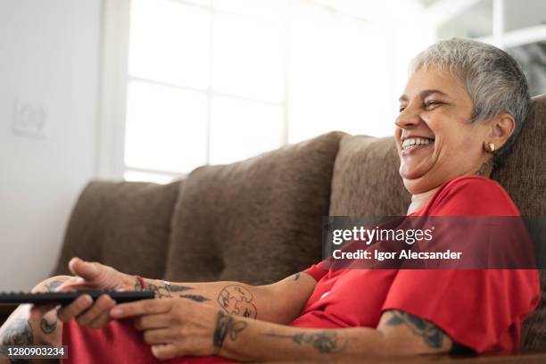 smiling at home watching tv - old woman tattoos stock pictures, royalty-free photos & images