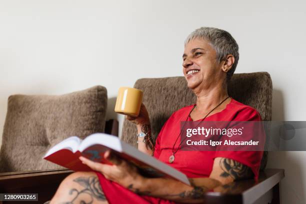enjoying coffee and reading at home - old woman tattoos stock pictures, royalty-free photos & images