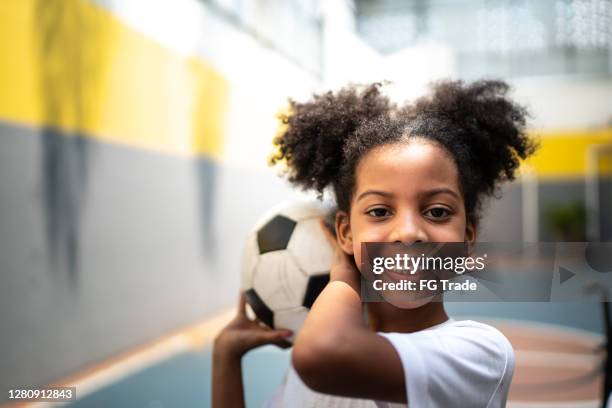 portret van een gelukkig meisje dat een voetbalbal tijdens fysieke activiteitsklasse houdt - player portraits stockfoto's en -beelden