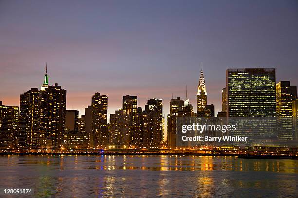 dusk view of empire state building, chrysler building, united nations headquarters building, and towers of manhattan's east side, from gantry plaza state park, hunter's point, long island city, queens, new york, u.s.a. - queensday stock-fotos und bilder