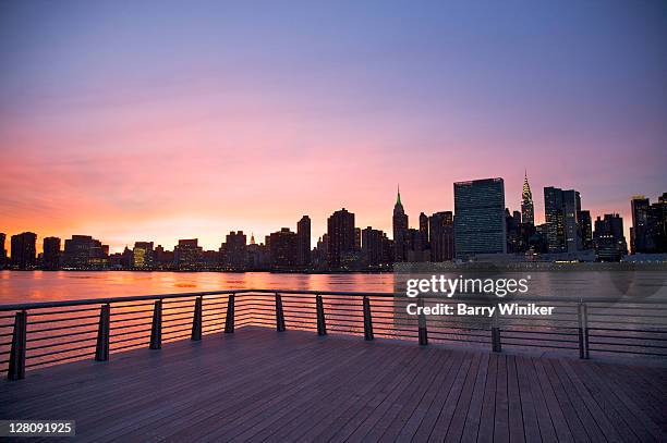 midtown manhattan at dusk, in distance viewed from the corner of pier at gantry plaza state park, hunter's point, long island city, queens, new york, u.s.a. - east river stock-fotos und bilder